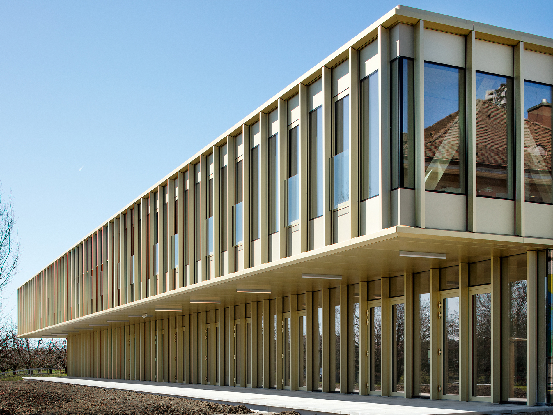 Auskragendes neues Obergeschoss auf saniertem Erdgeschoss des Schulhauses in Sutz-Lattrigen (© Indermühle Bauingenieure)