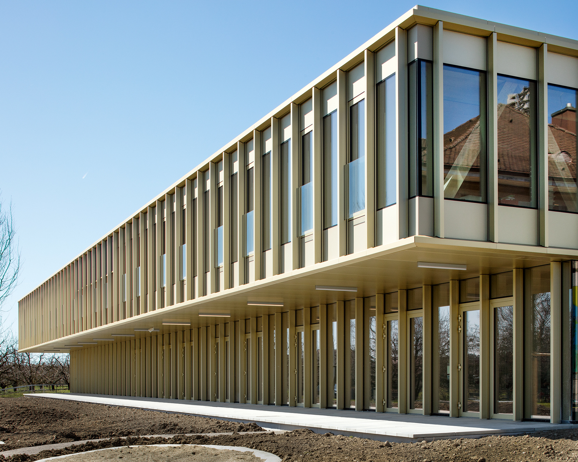 Auskragendes neues Obergeschoss auf saniertem Erdgeschoss des Schulhauses in Sutz-Lattrigen (© Indermühle Bauingenieure)